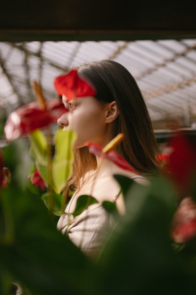 白天在白色礼服衬衫的女人举着红色的花
